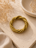 Pulsera trenzada dorada tipo snake sobre piedra