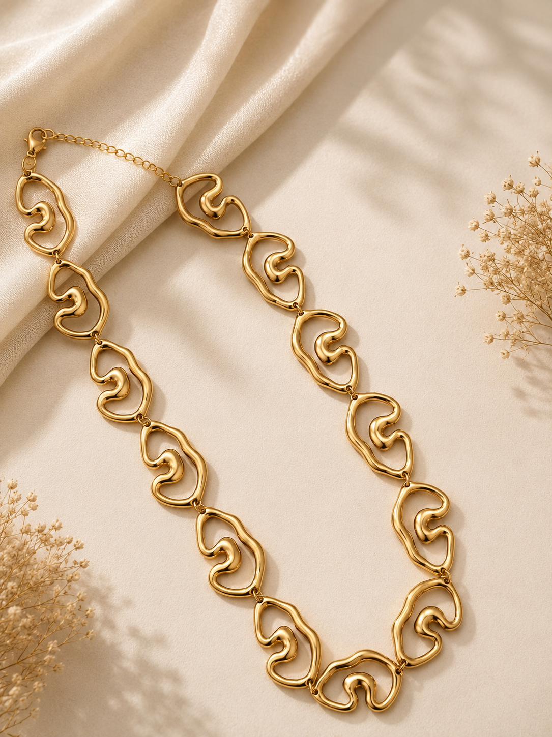 Collar eslabones ondulados dorado sobre tela blanca