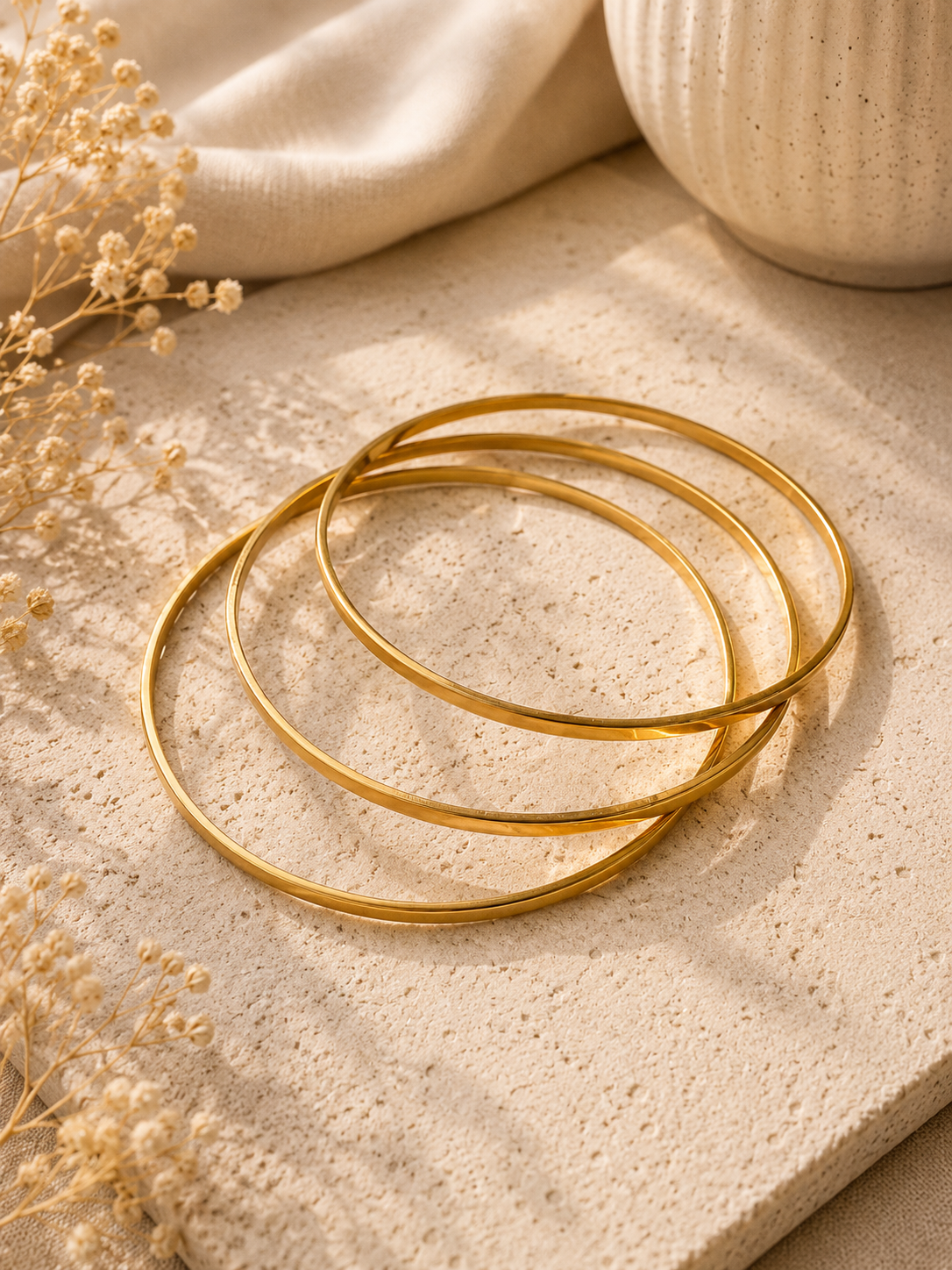 Set de 3 bangles dorados minimalistas sobre piedra