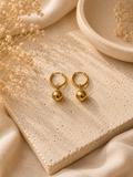 Aretes argolla dorada con dije de esfera pulida sobre piedra beige