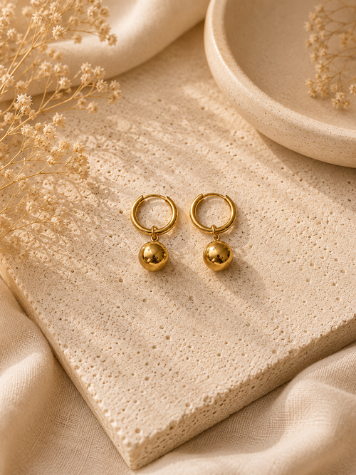 Aretes argolla dorada con dije de esfera pulida sobre piedra beige