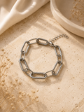 Pulsera cadena eslabón plateada con textura trenzada sobre piedra