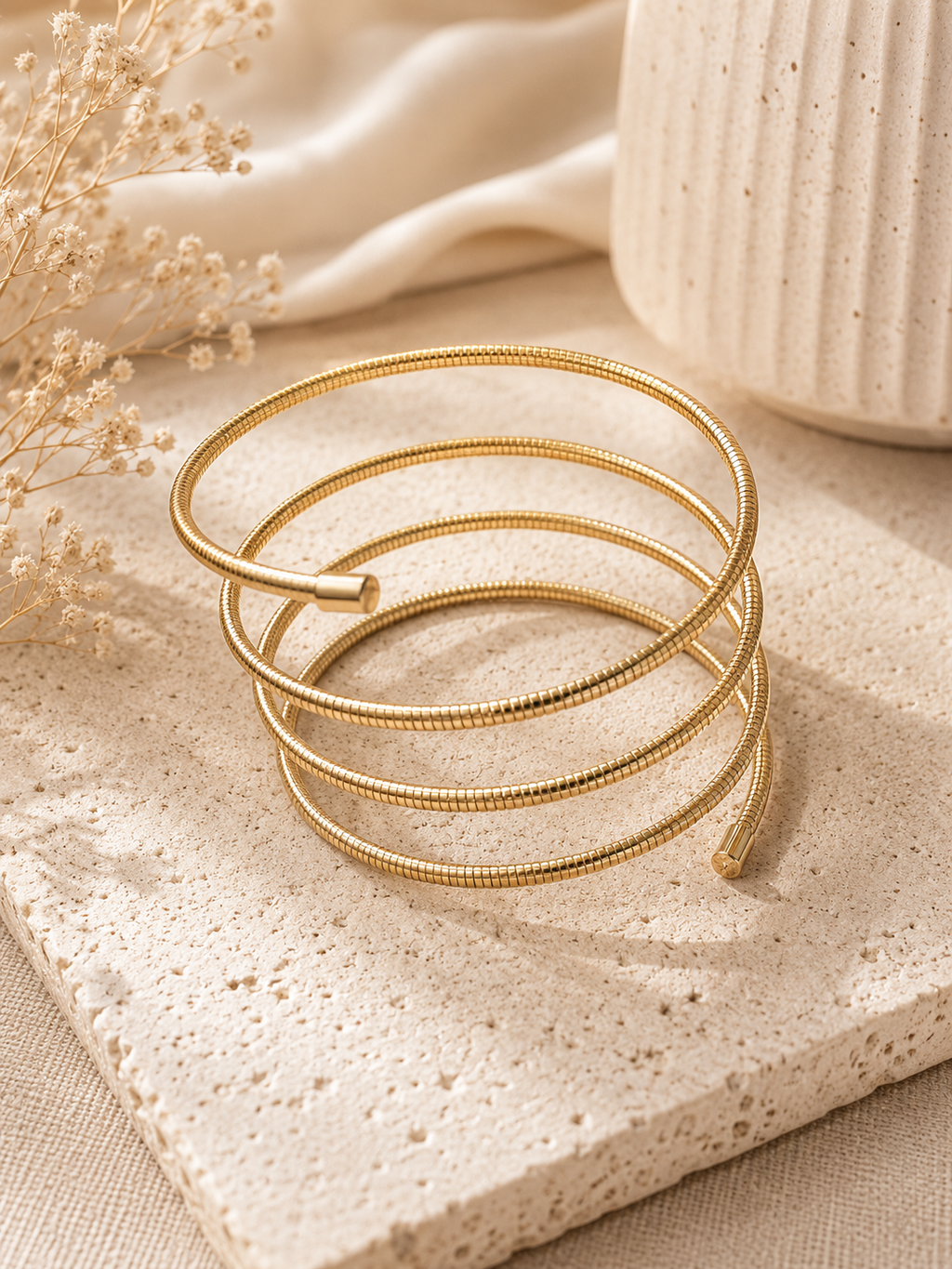 Pulsera espiral dorada sobre superficie de piedra
