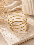 Pulsera espiral dorada sobre superficie de piedra