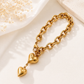 Pulsera cadena dorada con dije de corazón inflado sobre superficie blanca