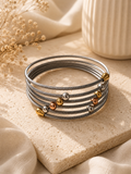Pulsera de cable trenzado plateado con esferas tricolor sobre piedra