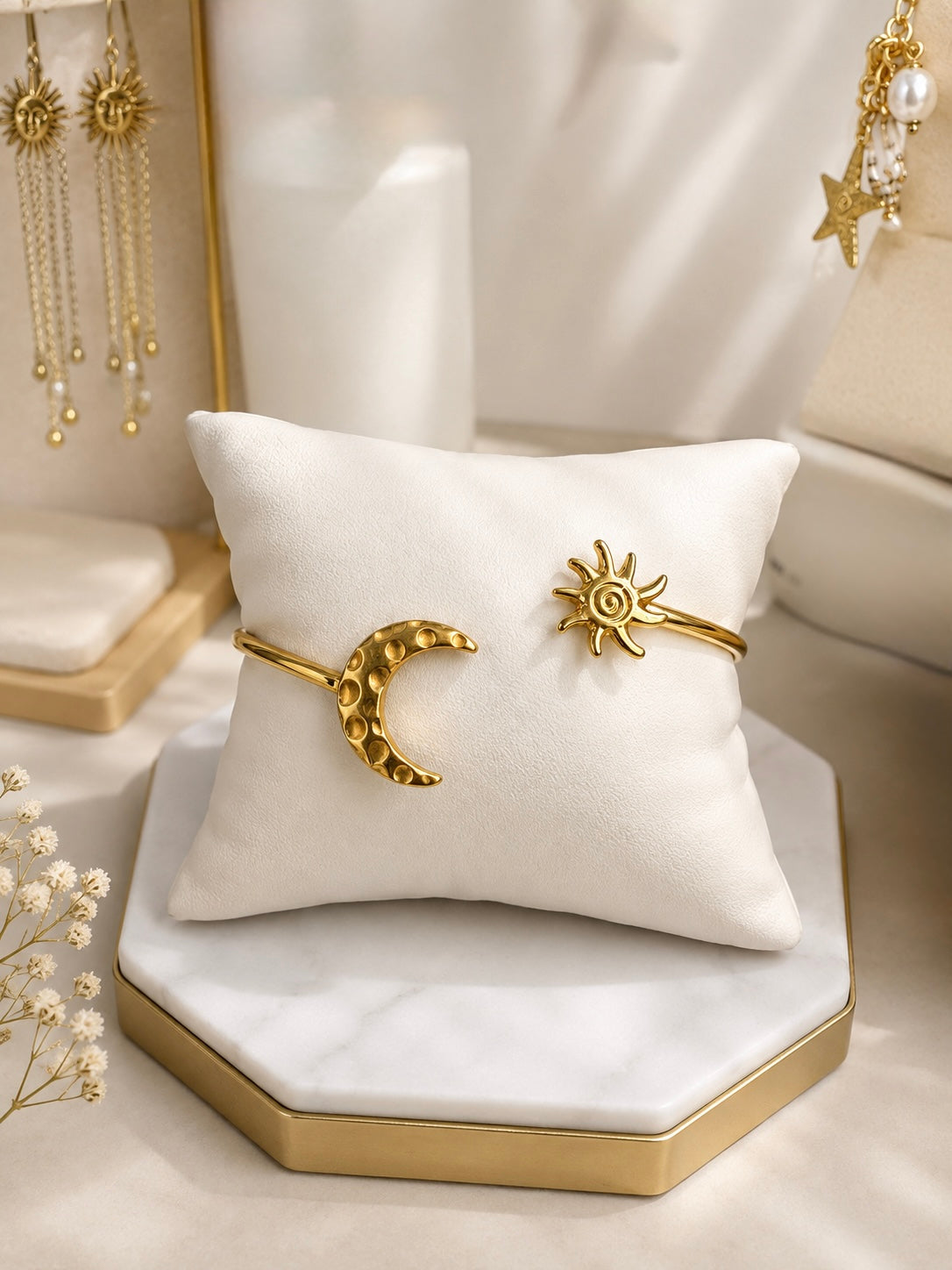 Set de dos brazaletes dorados rígidos: uno con luna creciente martillada y otro con sol espiral sobre almohada de exhibición