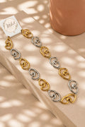Collar eslabones corazón bicolor dorado y plateado sobre superficie beige