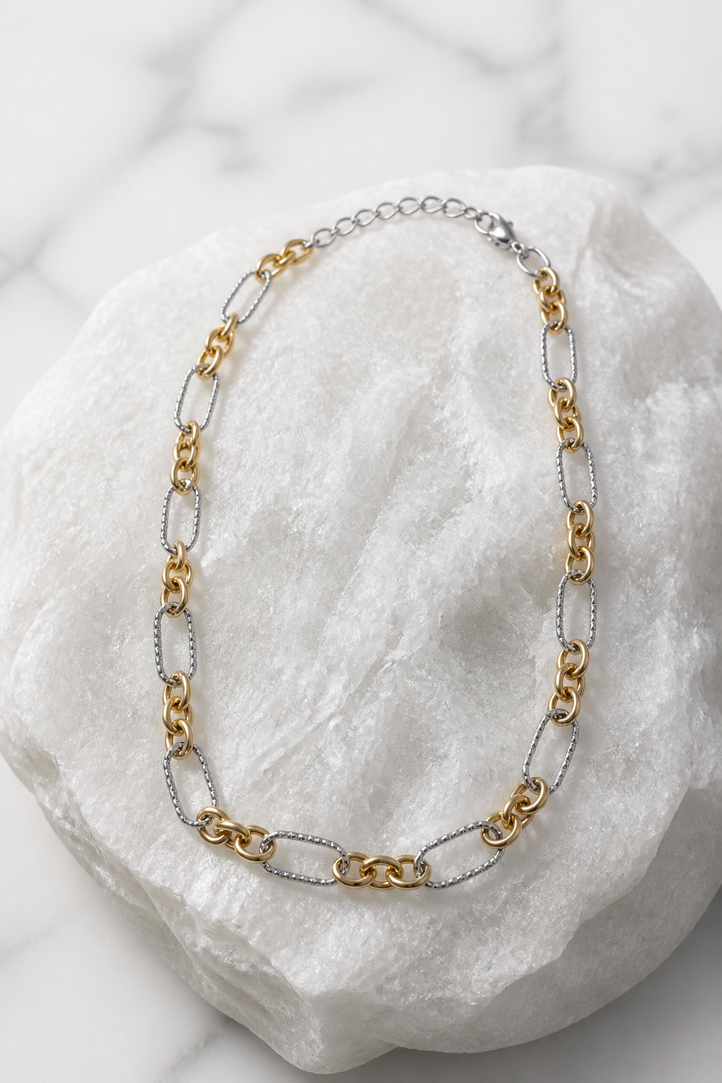 Collar cadena bicolor eslabones alternados dorado y plateado sobre mármol blanco