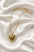 Collar dorado con dije de corazón rodeado de perlas sobre seda