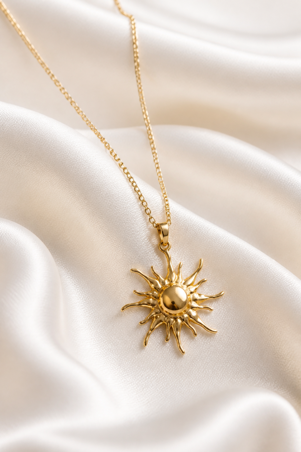 Collar con colgante de sol dorado sobre tela blanca